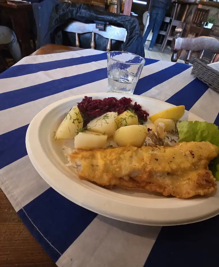 Smażony filet z dorsza z ziemniakami i surówkami na obrusie w granatowo-białe pasy